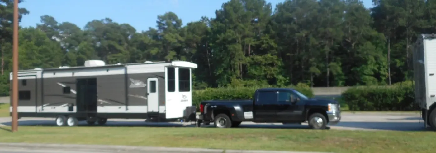 A dual-rear-wheel pickup towing a large travel trailer: every rating on the door applies at once.