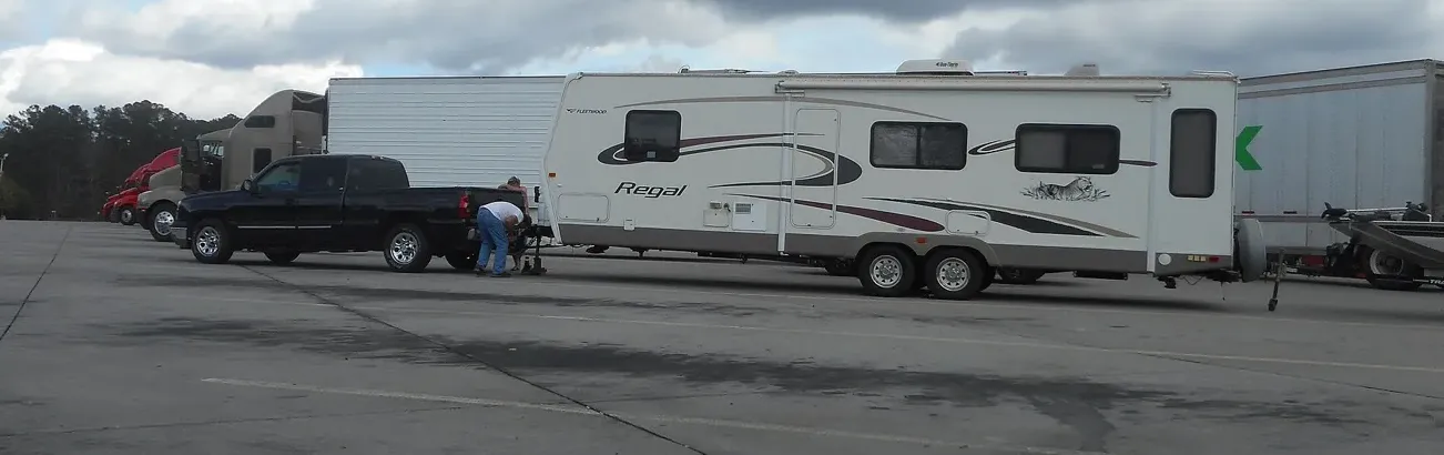 A pickup with a travel trailer at a highway rest area. The tongue on that ball is part of the truck's payload.